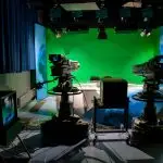 A TV studio setup featuring cameras and a green screen for production purposes.